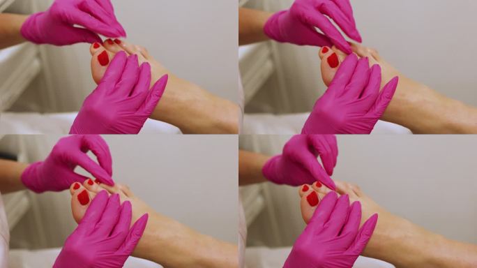 女士在Spa沙龙接受经典的红指甲足疗-角质层油程序。腿部和指甲皮肤护理。足疗程序和SPA。特写，选择