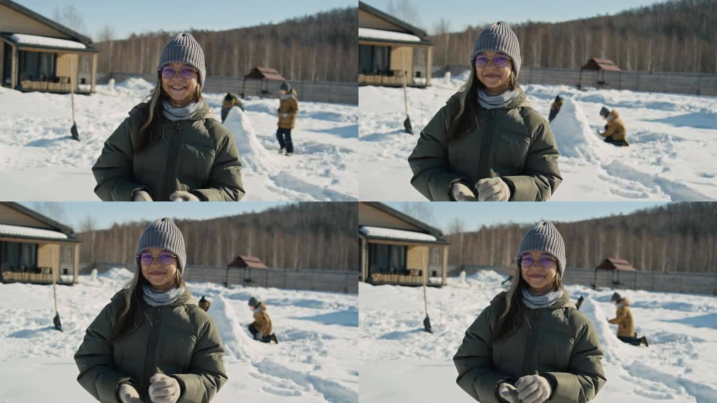 微笑的白人女孩在户外做雪球的肖像