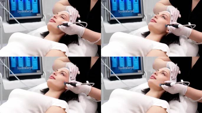 美容诊所。专业女美容师在工作时正在做面部补水手术。漂亮的女人躺在医疗床上做美容手术