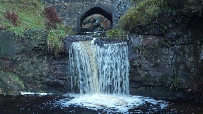 水流入天然水池。小溪上的小石桥，英国乡村