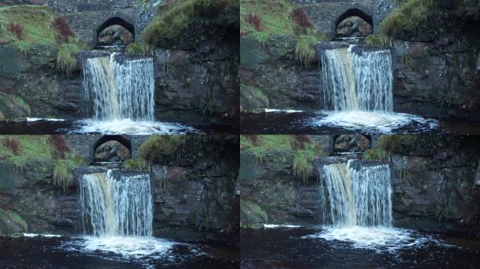 水流入天然水池。小溪上的小石桥，英国乡村