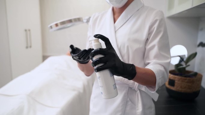 美容师在水疗中心为面部护理准备洗面奶。专家在美容诊所将产品涂在戴手套的手上。护肤专家准备抗衰老程序。