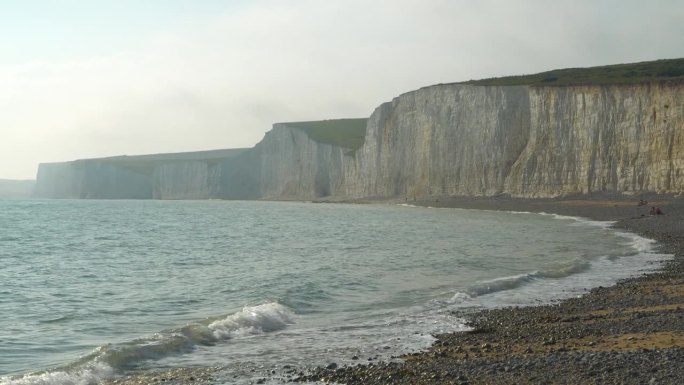 风景如画的白色悬崖耸立在波涛汹涌的大海之上，下面是岩石海滩