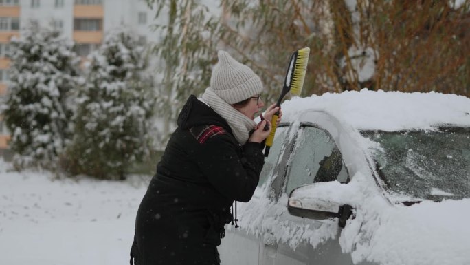 漂亮女人一边擦车里的雪，一边涂嘴唇。