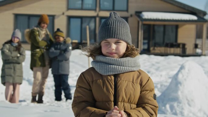 小孩子在户外打雪仗，眯着眼睛望着太阳