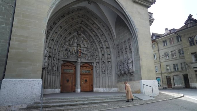 弗里堡，瑞士，大约2022年3月——人进入教堂。弗里堡圣尼古拉斯大教堂的外观
