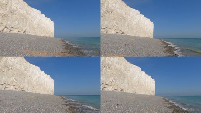 令人难以置信的壮观的白色悬崖矗立在蓝色的海洋旁的岩石海滩上