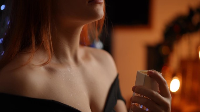 一个穿着鸡尾酒会礼服的年轻女子在身体暴露的部位喷洒香水的特写镜头。