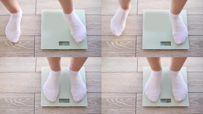 穿着白袜子的女人的腿踩在地秤上。54公斤