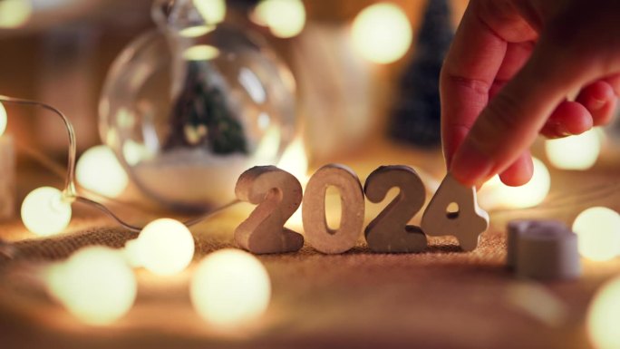 女人的手把2024数字装饰的桌子上，圣诞快乐，新年快乐!