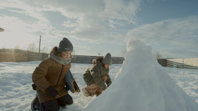 两个孩子保护雪堡，并向敌人队扔雪球