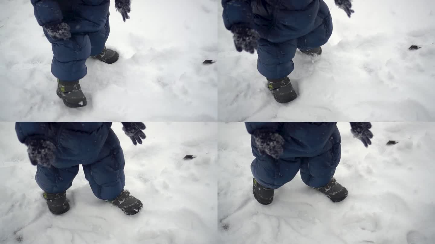 一个小孩走过刚下过的雪。一个穿着羽绒服的男孩踩在雪地上留下了脚印。腿收起来。缓慢的运动。FHD