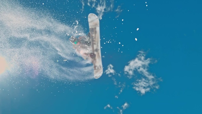 在阳光明媚的日子里，滑雪板运动员的SLO MO。男子正在雪山上玩单板滑雪。他喜欢冬季运动。