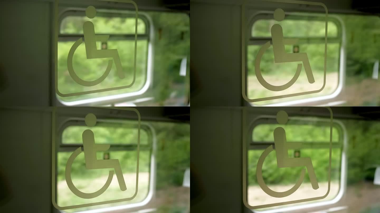 一列正在行驶的火车车厢的窗户侧面挂着“残疾人”的标志，背景是绿树。
