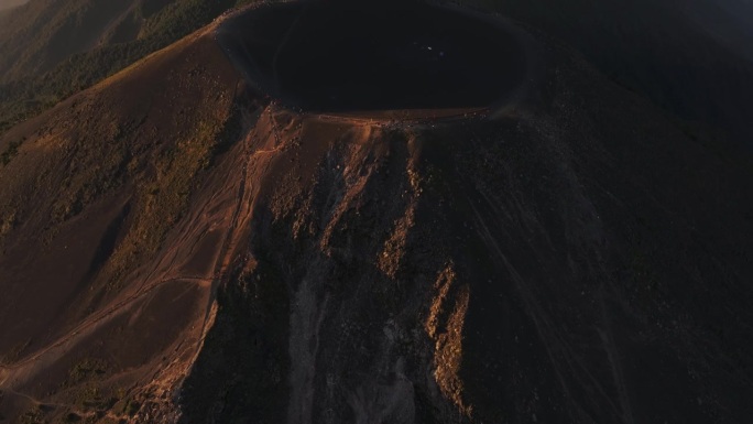 在冒烟的火山前一个空火山口的游客俯视图