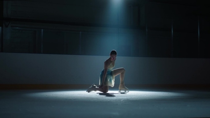 美丽的女花样滑冰运动员独自在黑暗的溜冰场跳舞，慢动作，浪漫的舞蹈表演