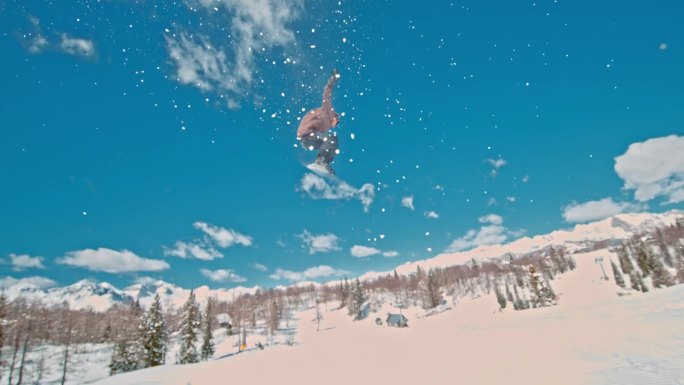 SLO MO -时间扭曲效果/速度斜坡的男子练习特技与滑雪板在阳光明媚的日子。图为，一名滑雪者在蓝天
