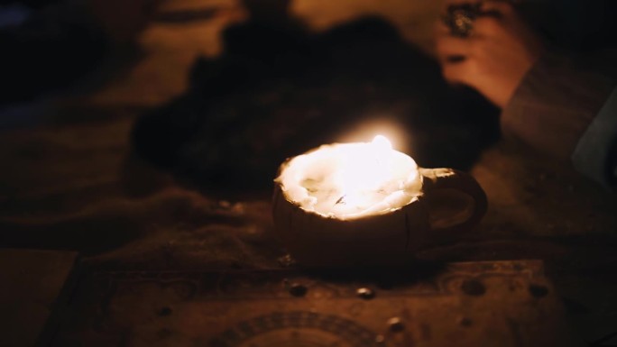 在一张大木桌上有一个杯子和蜡烛，照亮了整个房间。近距离射击