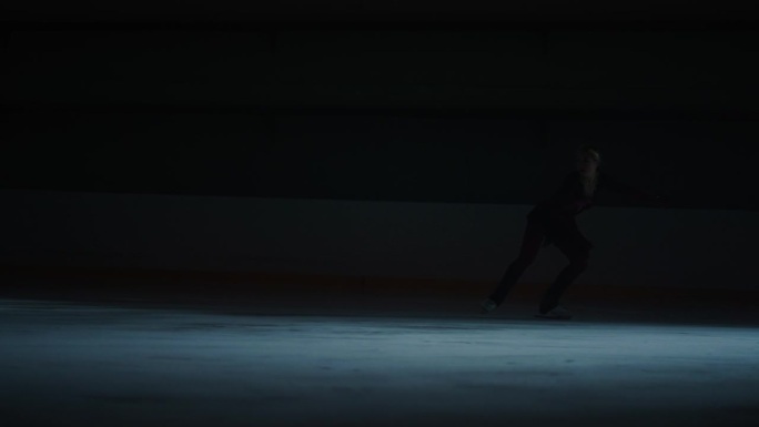 专业冰上表演，优雅的女人独自在冰上跳舞在黑暗中，剪影拍摄，慢动作