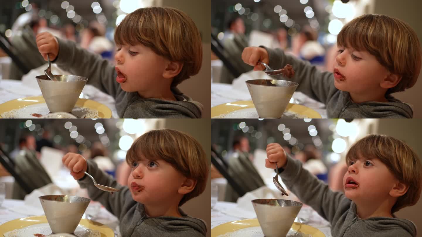 孩子在餐厅拿着勺子吃着冰淇淋甜点，小男孩在晚餐后喜欢吃含糖的食物