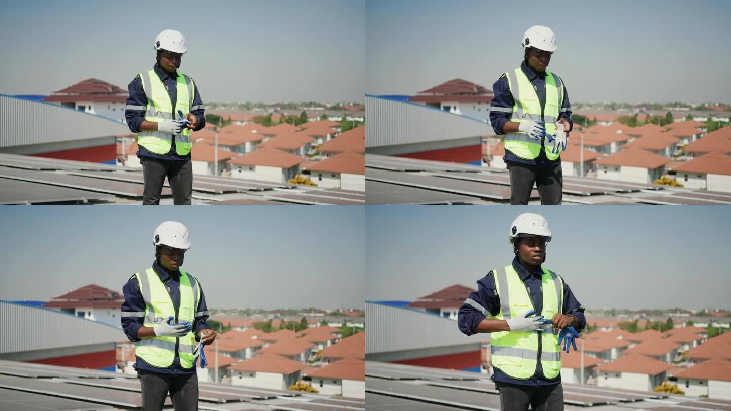一位非洲男性电力工人在屋顶上利用太阳能的肖像-清洁和绿色能源生产。
