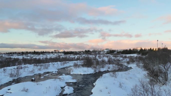 冰岛的冬天。从空中俯瞰河流。雷克雅未克的日出。白雪覆盖的城市，阳光明媚的早晨。