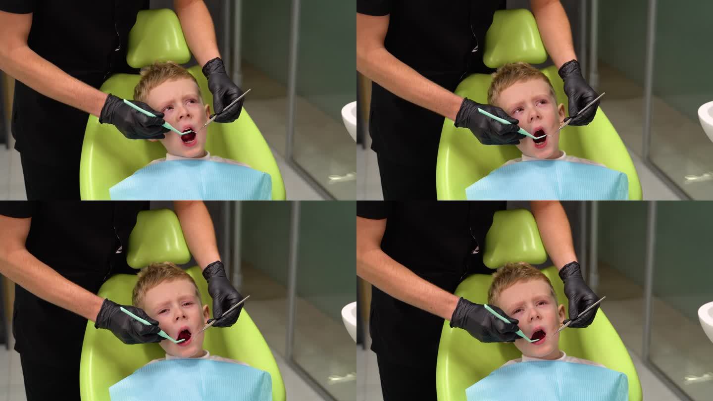 悲伤的小男孩在牙医治疗牙齿时张大了嘴巴。孩子不敢治牙