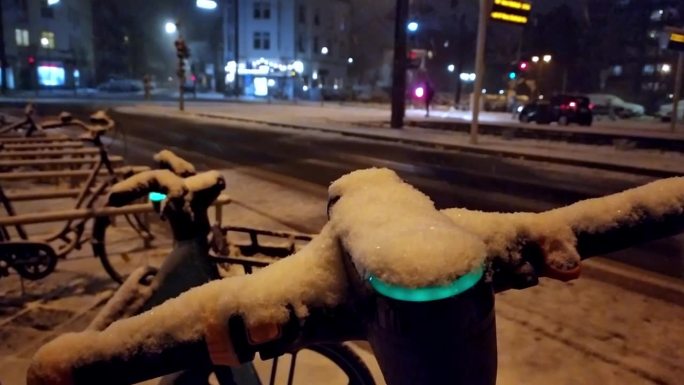 雪天的冬夜，在雪天的城市街道上使用电动滑板车或机动自行车共享概念，展示了像电动汽车一样在现代城市生活