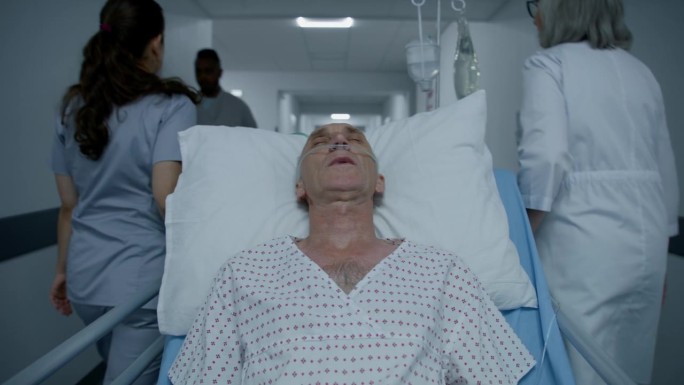 老年病人术后带着呼吸管睡在轮床上。