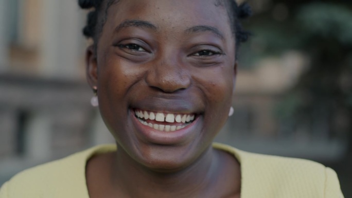 快乐的非裔美国妇女在城市户外笑着表达幸福的特写肖像