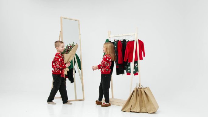 浅色背景下的孩子们在更衣室里，背景是挂着孩子衣服的衣架。圣诞夜的小时尚达人。