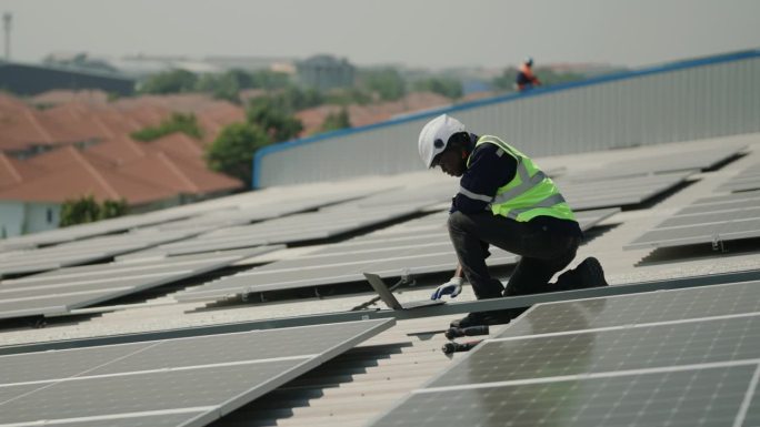 可持续能源:身穿制服的非洲工程师为屋顶太阳能电池板进行可靠的能源检查。