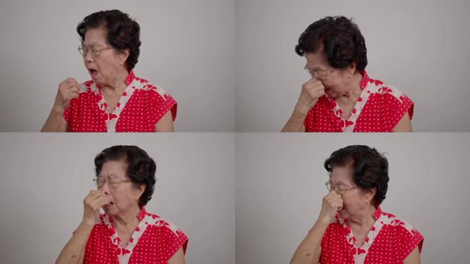 老年亚洲妇女鼻塞空气过敏和大量的灰尘，老年妇女擤她的鼻子。老太太得了感冒或流感，感到悲伤，流鼻涕