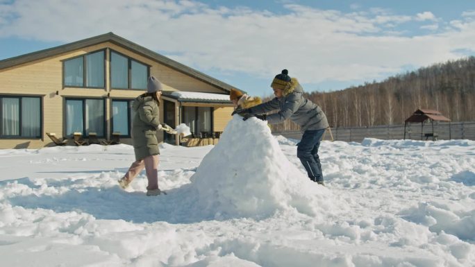 阳光明媚的日子里，一群不同的孩子在后院堆雪城堡