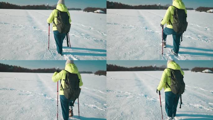 一位年长的女徒步旅行者背着双肩包，穿着雪鞋，在寒冷的冬季森林中漫步在白雪覆盖的道路上。冬季体育活动。