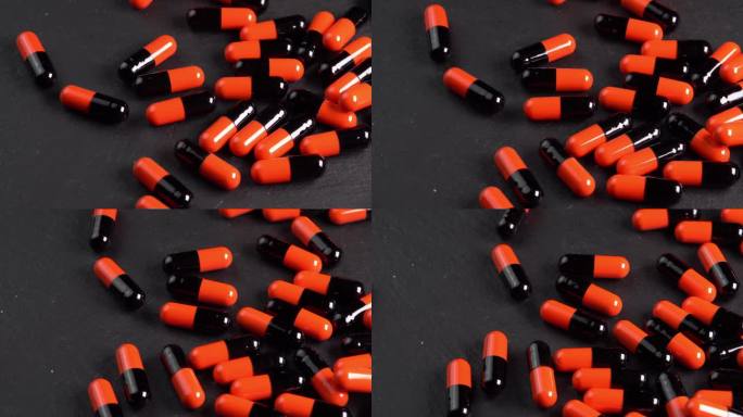 许多黑色和橙色药丸胶囊或抗抑郁药倒在黑色的宏板上。止痛头痛的药物或药物。制药行业