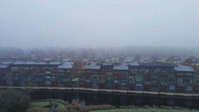 在浓雾中，运河附近的一排房子的美丽的三角帆。