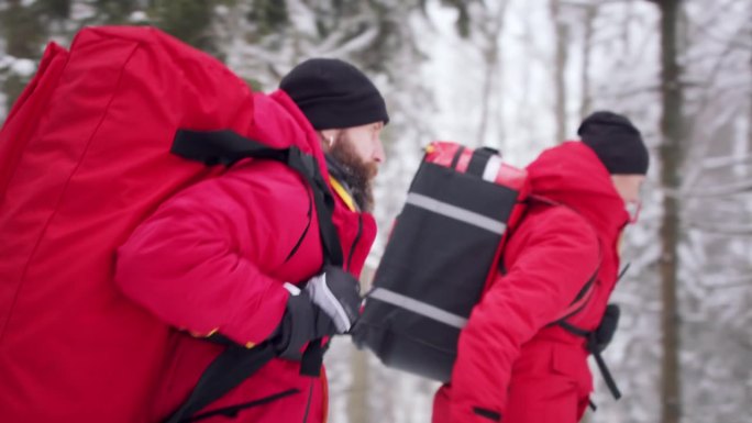 冬季在森林中进行户外登山救援服务的医护人员的侧视图。