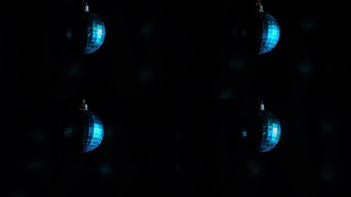 装饰镜球与蓝色反射旋转在黑色背景与复制空间。旋转新年玻璃球。