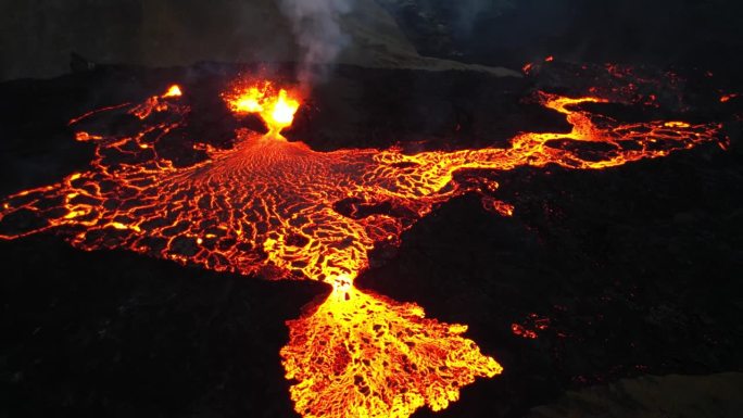 无人机拍摄的从活火山火山口流出的红色炽热熔岩。夜间航拍的明亮熔岩。岩浆从火山口喷出。冰岛火山。火山口