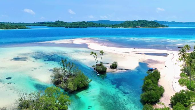 鸟瞰在印尼明打威海绵宝宝岛碧绿的海水中，一个人坐在白色的桨板上。