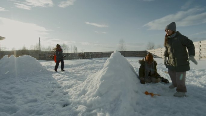 阳光灿烂的日子里，孩子们在院子里打雪仗