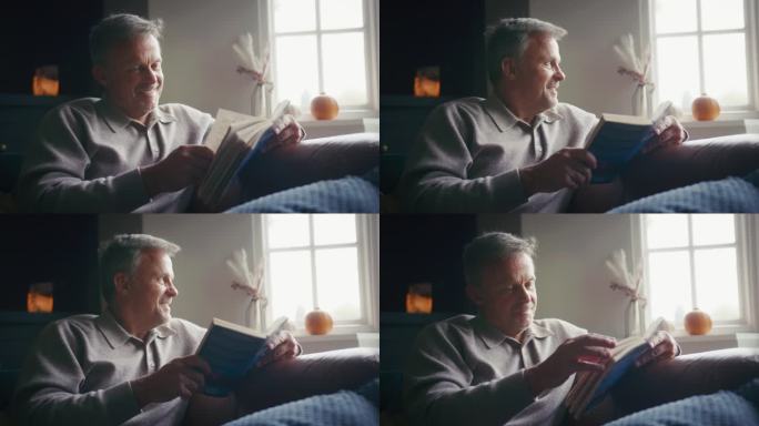 冬天，成熟的男人在家穿毛衣，躺在沙发上看书