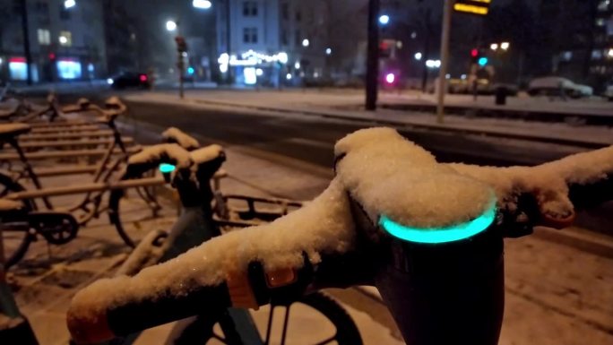 雪天的冬夜，在雪天的城市街道上使用电动滑板车或机动自行车共享概念，展示了像电动汽车一样在现代城市生活