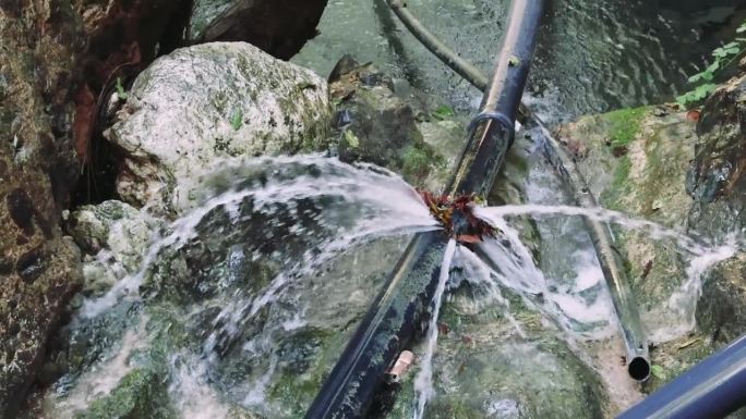 管道漏水对环境造成破坏，石头间漏水。特写环境破坏，彰显大自然的抗争。管道泄漏，环境破坏的一个鲜明例子