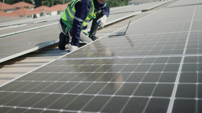 专业技术工人用笔记本电脑检查屋顶太阳能电池板。