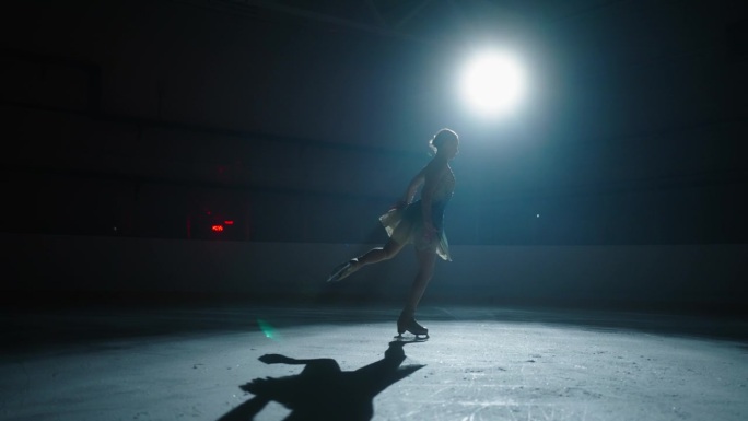 在黑暗的溜冰场上独自滑冰的优雅女子剪影，艺术和运动的展示