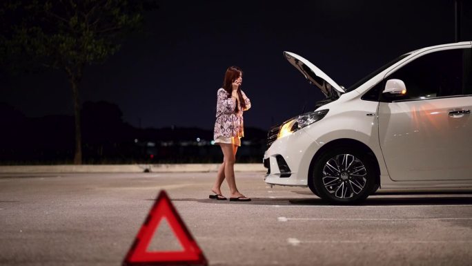 亚洲华人女士的车在露天停车场抛锚了