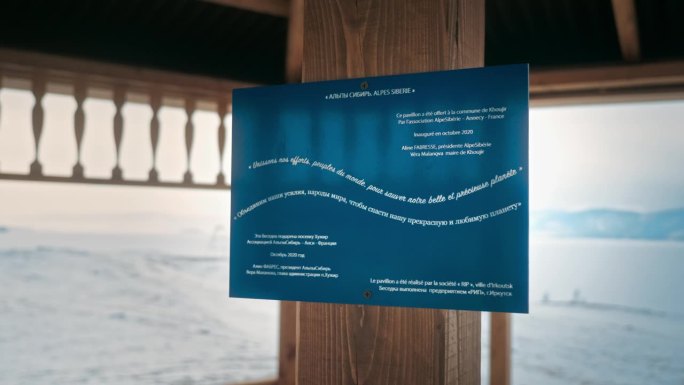 贝加尔湖凉亭上的蓝色旅游信息牌，上面写着西伯利亚阿尔卑斯山。在背景中，你可以看到冬天的景色。俄罗斯奥