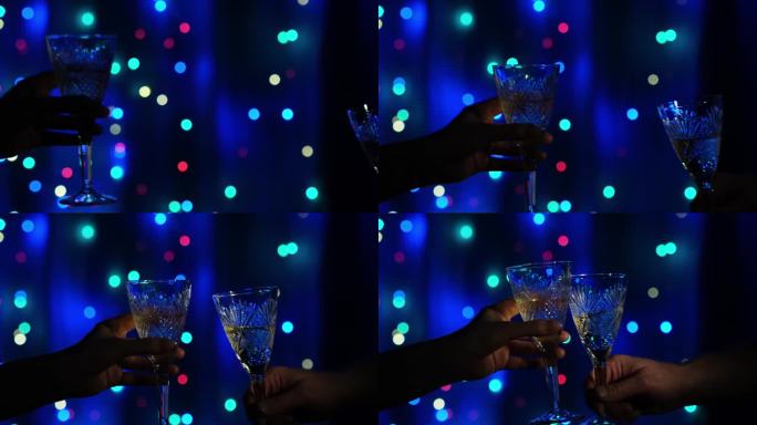 一对叮当作响的水晶酒杯，在闪烁的花环背景上装满了香槟。为新的开始干杯。新年快乐，圣诞快乐。